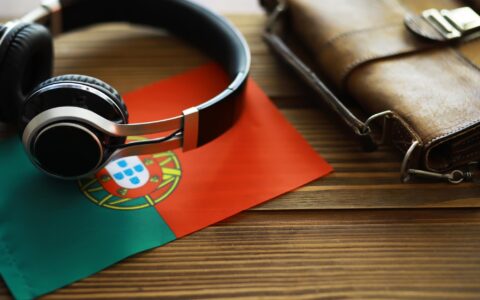 Fones de Ouvido e Bolsa de Couro sobre a Bandeira Portuguesa, Equipamento de Áudio em Mesa de Madeira