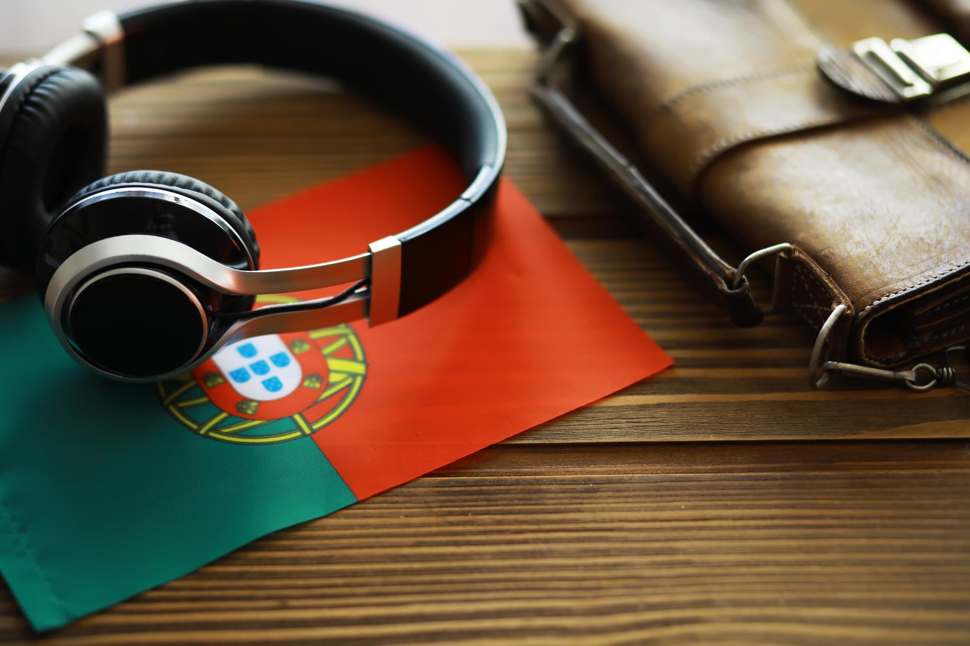 Fones de Ouvido e Bolsa de Couro sobre a Bandeira Portuguesa, Equipamento de Áudio em Mesa de Madeira